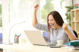 50532398 – euphoric winner watching a laptop on a desk winning at home